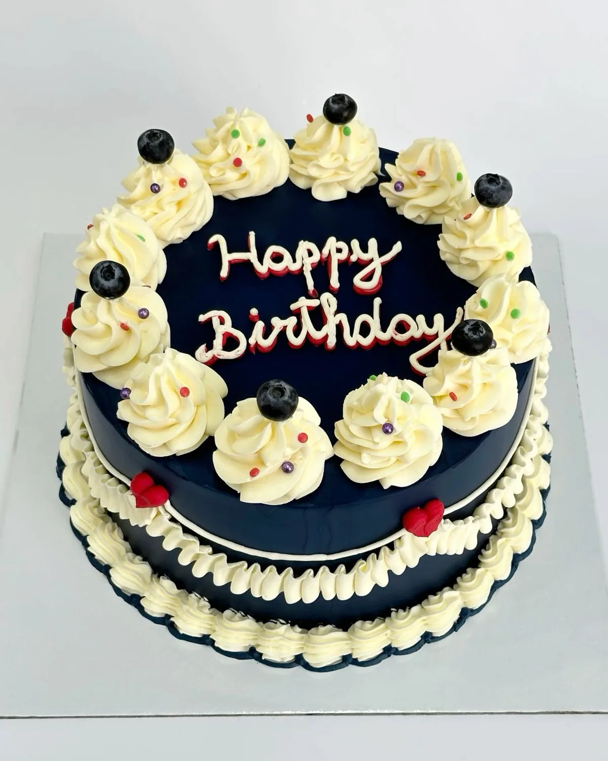 Navy birthday cake with cream swirls, blueberries and piped lettering, a custom cake by Cakes By Vjollca in Pristina, Kosovo