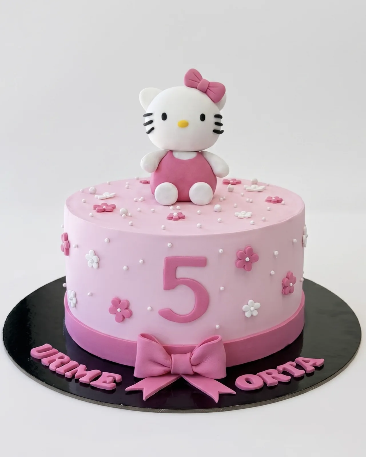 Pink Hello Kitty fifth birthday cake with a fondant figurine and flowers, a custom cake by Cakes By Vjollca in Pristina, Kosovo