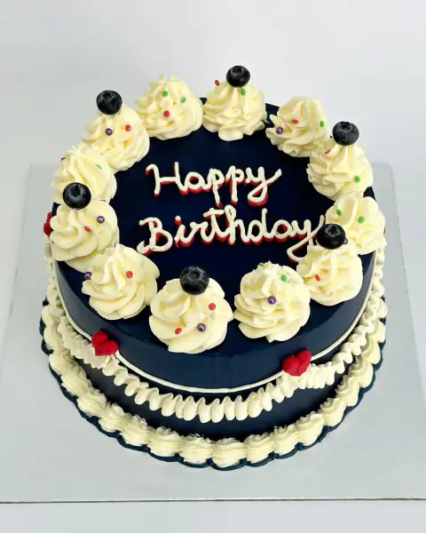 Navy birthday cake with cream swirls, blueberries and piped lettering, a custom cake by Cakes By Vjollca in Pristina, Kosovo