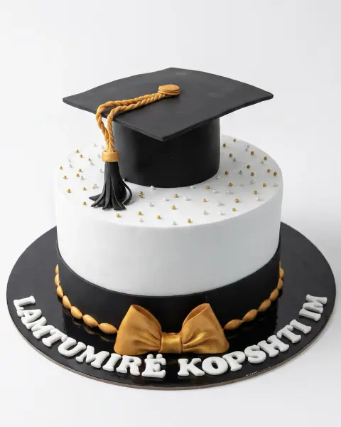 Black and white graduation cake with a fondant graduation cap and gold bow, a custom cake by Cakes By Vjollca in Pristina, Kosovo