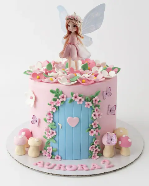 Pink fairy garden birthday cake with a fairy topper, flower door and toadstools, a custom cake by Cakes By Vjollca in Pristina, Kosovo